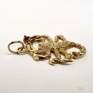 Gold scorpion pendant on white background.
