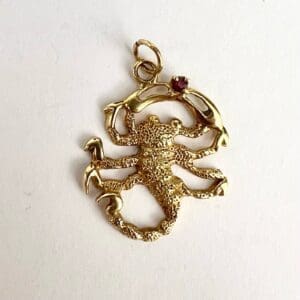 Golden scorpion pendant with small gemstone.