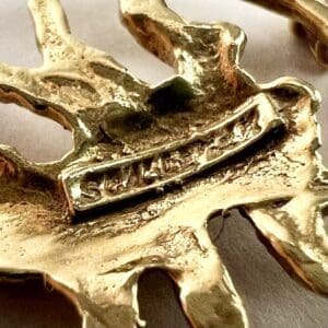 Gold-toned metal sculpture with engraved text.