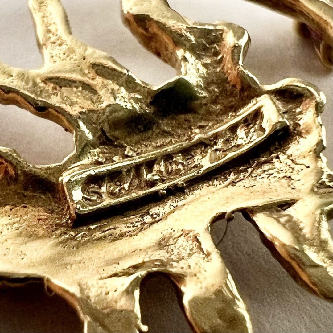 Gold-toned metal sculpture with engraved text.