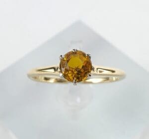 Gold ring with round yellow gemstone.