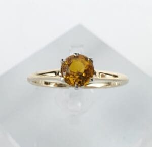 Gold ring with round yellow gemstone.