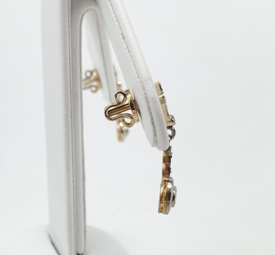 Gold jewelry displayed on white stand.