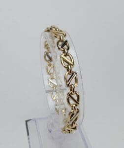 Gold chain bracelet on clear display stand.