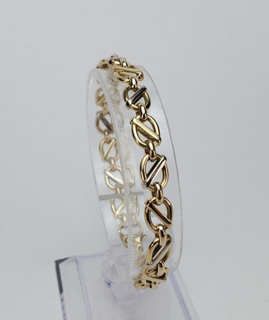 Gold chain bracelet on clear display stand.