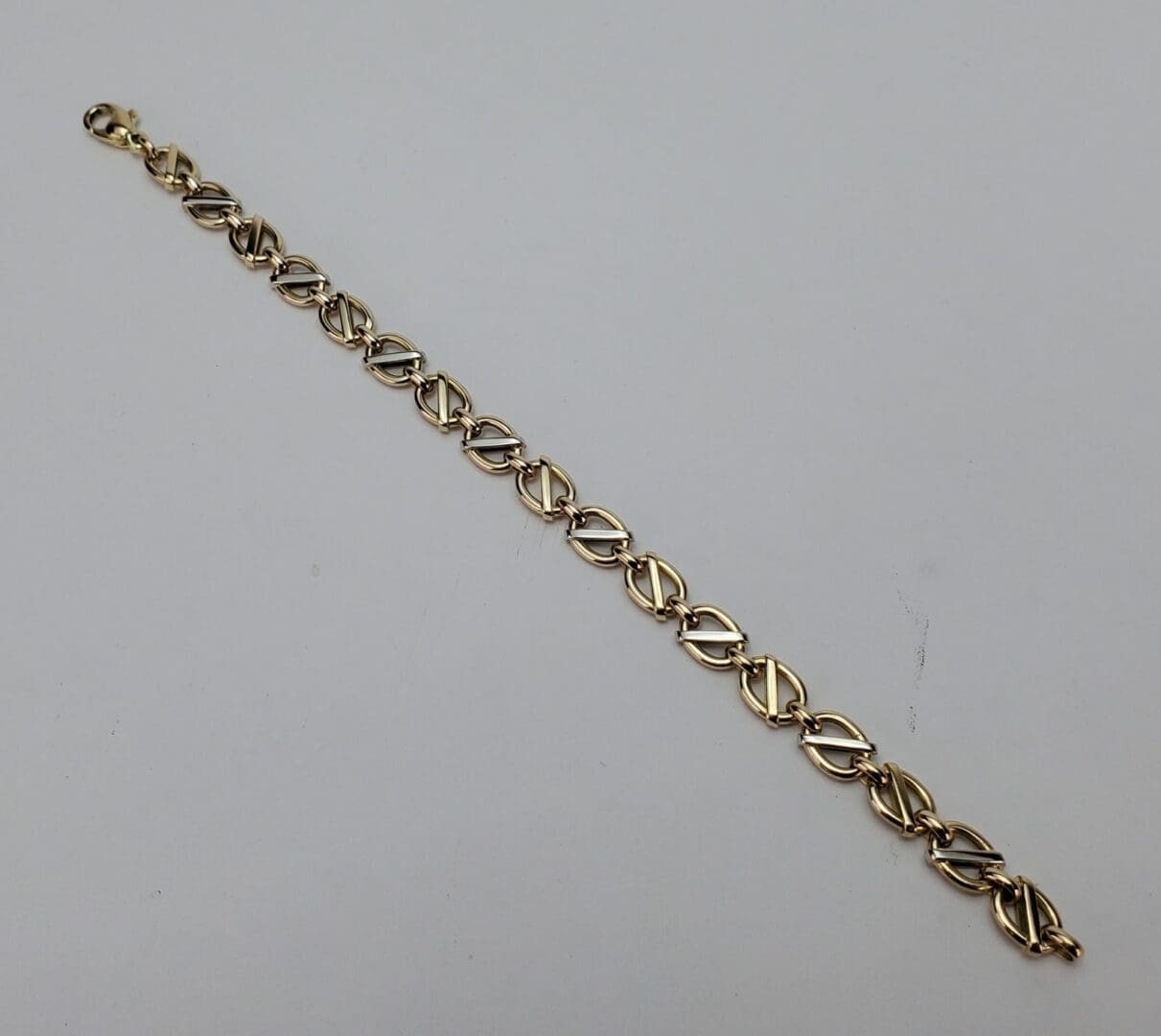 Gold chain bracelet on white background.