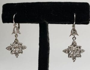 Silver floral earrings on display stand.