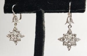 Silver star-shaped earrings on display stand.