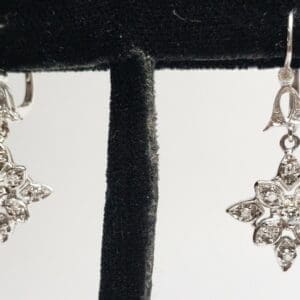 Silver star-shaped earrings on display stand.