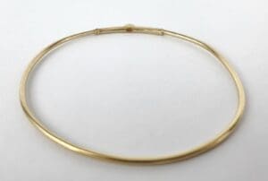 Gold bangle bracelet on white background.