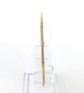 Gold bangle with single diamond detail.