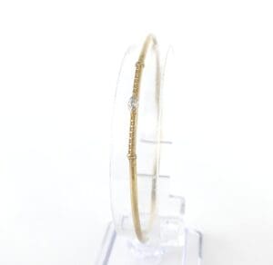 Gold bangle bracelet with diamond accent.