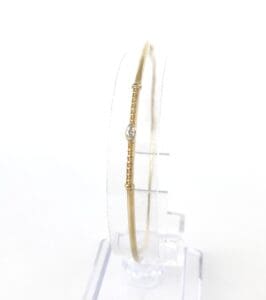 Gold bracelet with single diamond on stand.
