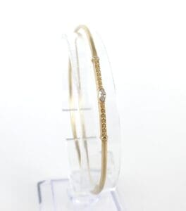Gold bangle with diamond on display stand.