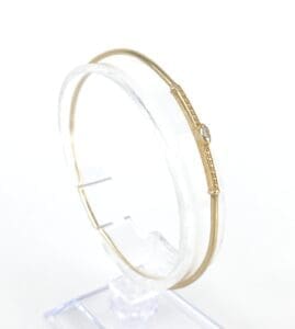 Gold bangle with small gemstone detail.