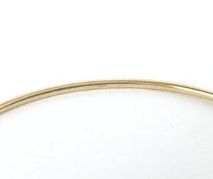 Thin gold bracelet on white background.