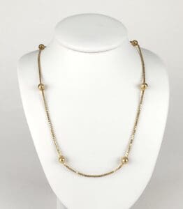 Gold necklace with spherical beads on display.