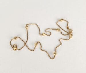 Gold chain necklace with spherical beads.