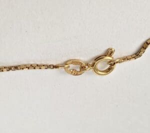 Gold necklace clasp on white background.