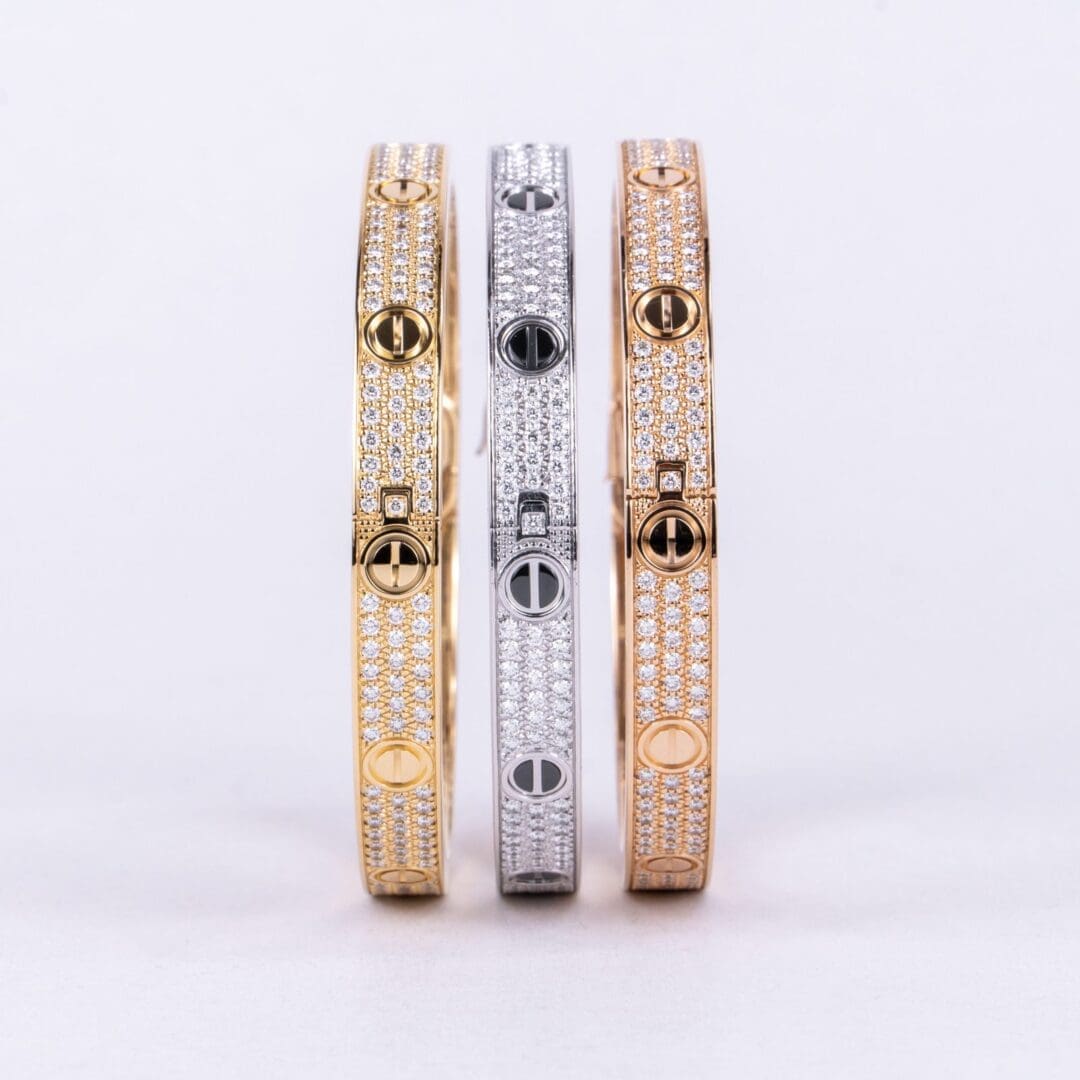 Three diamond-encrusted bracelets in gold tones.
