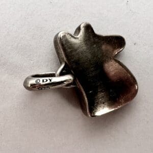 Silver pendant with engraved initials and numbers.