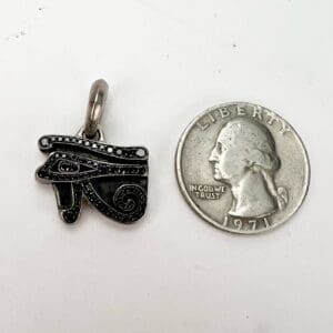 Eye of Horus pendant beside a quarter.