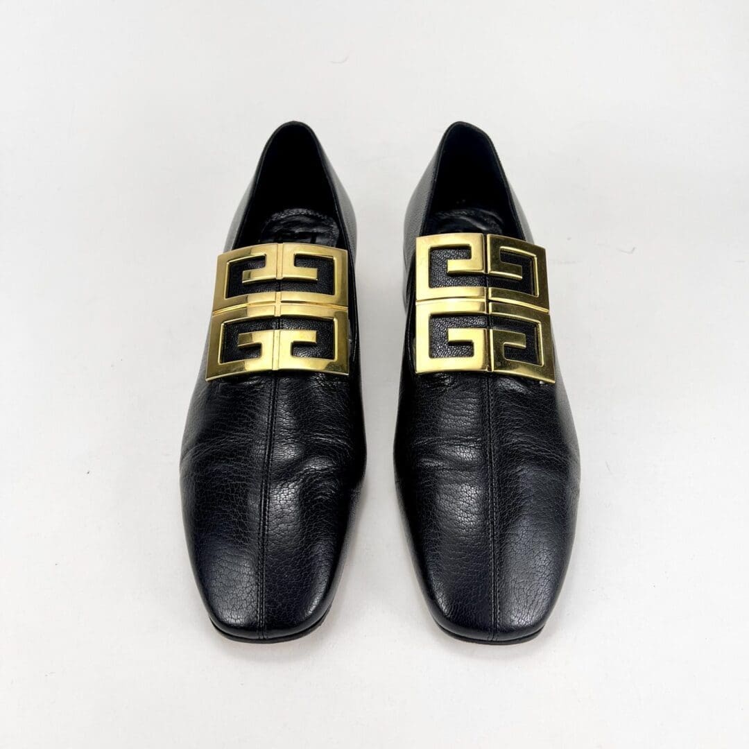 Black loafers with gold decorative buckles.