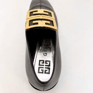 Black shoe with gold decorative buckle.