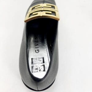 Black shoe with gold buckle design.