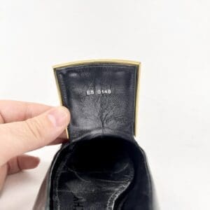 Hand holding a black leather shoe.