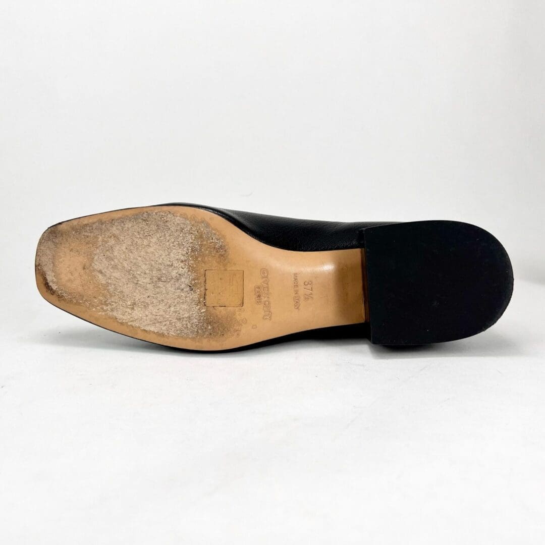 Black shoe with worn sole, side view.