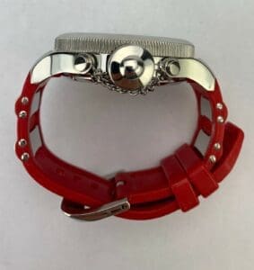 Watch with red strap, viewed from side.