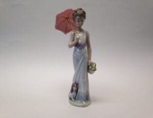 Porcelain figurine with parasol and small dog.