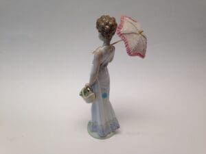 Porcelain lady figurine with umbrella and basket.