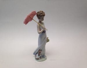 Porcelain figurine with parasol and small dog.