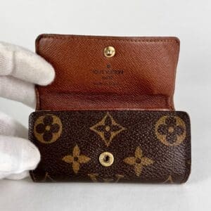 Brown monogram wallet held in gloved hand.