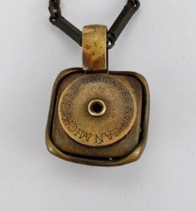 Antique brass pendant with engraved text.