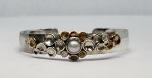 Silver bracelet with pearl and circular designs.