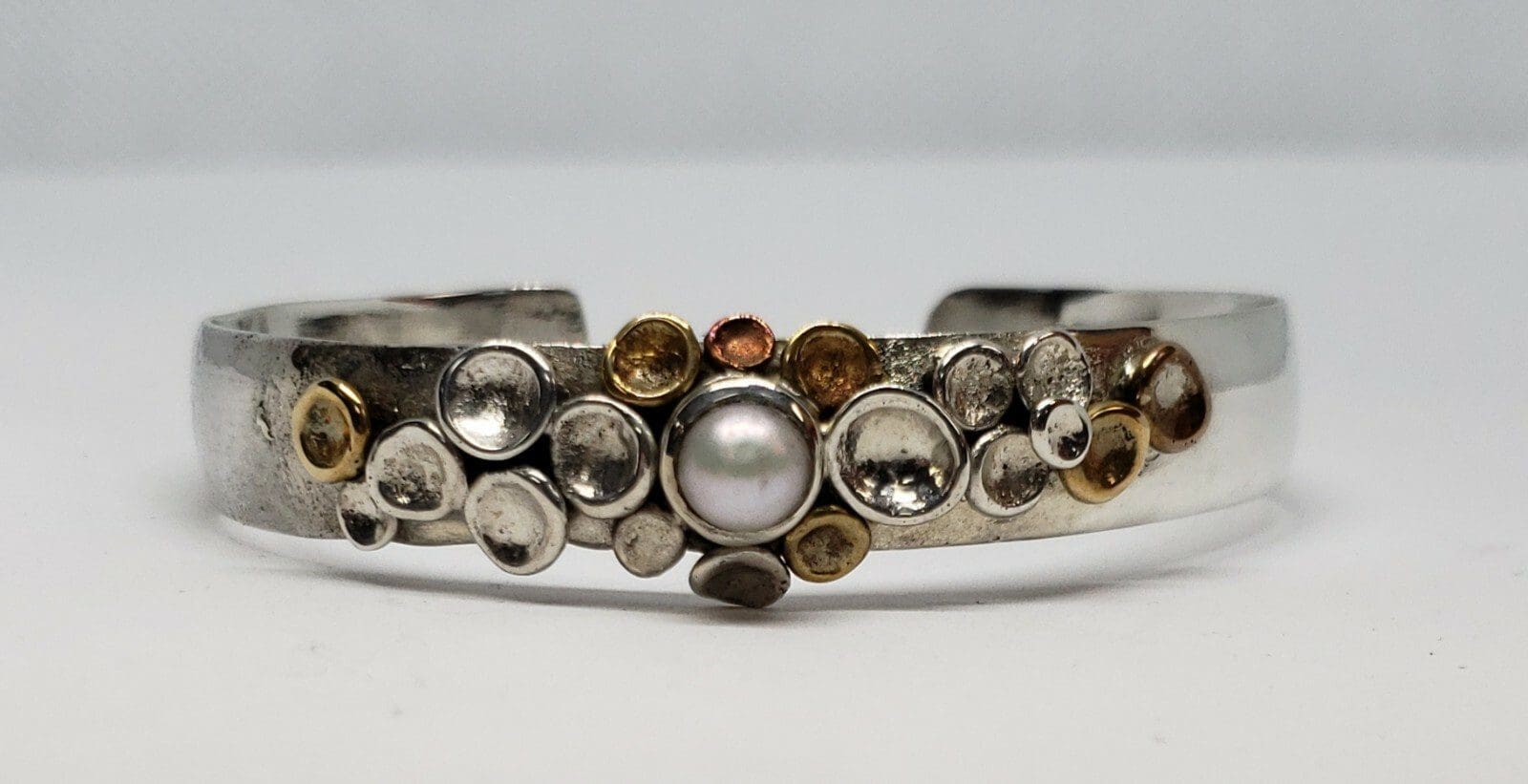 Silver bracelet with pearl and circular designs.