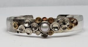 Silver bracelet with pearl and decorative circles.