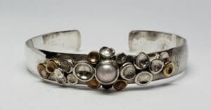 Silver bracelet with pearl and metal accents.