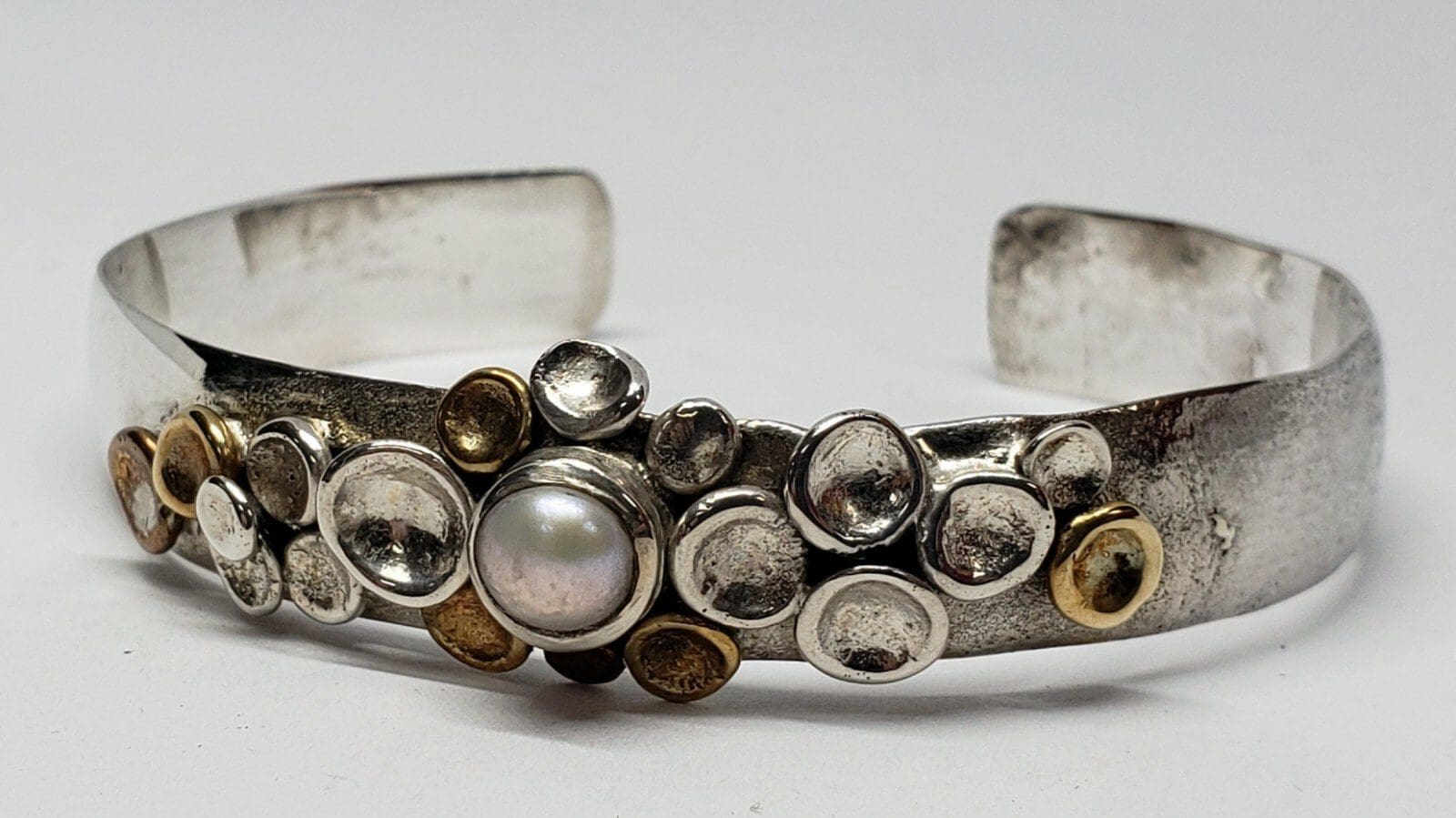 Silver bracelet with pearl and metal accents.