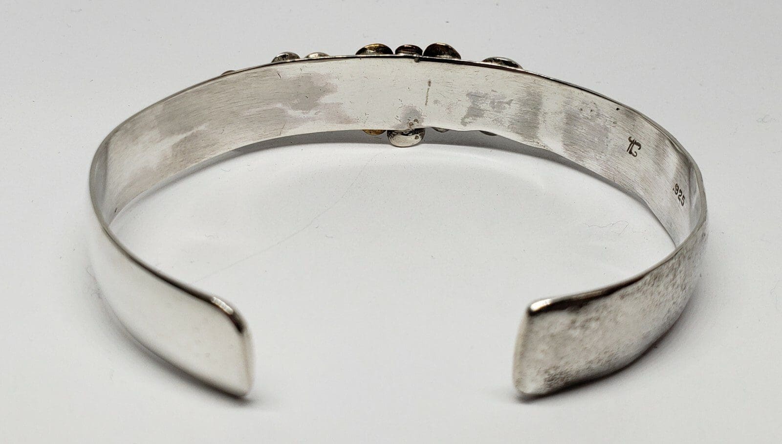 Silver cuff bracelet on white background.