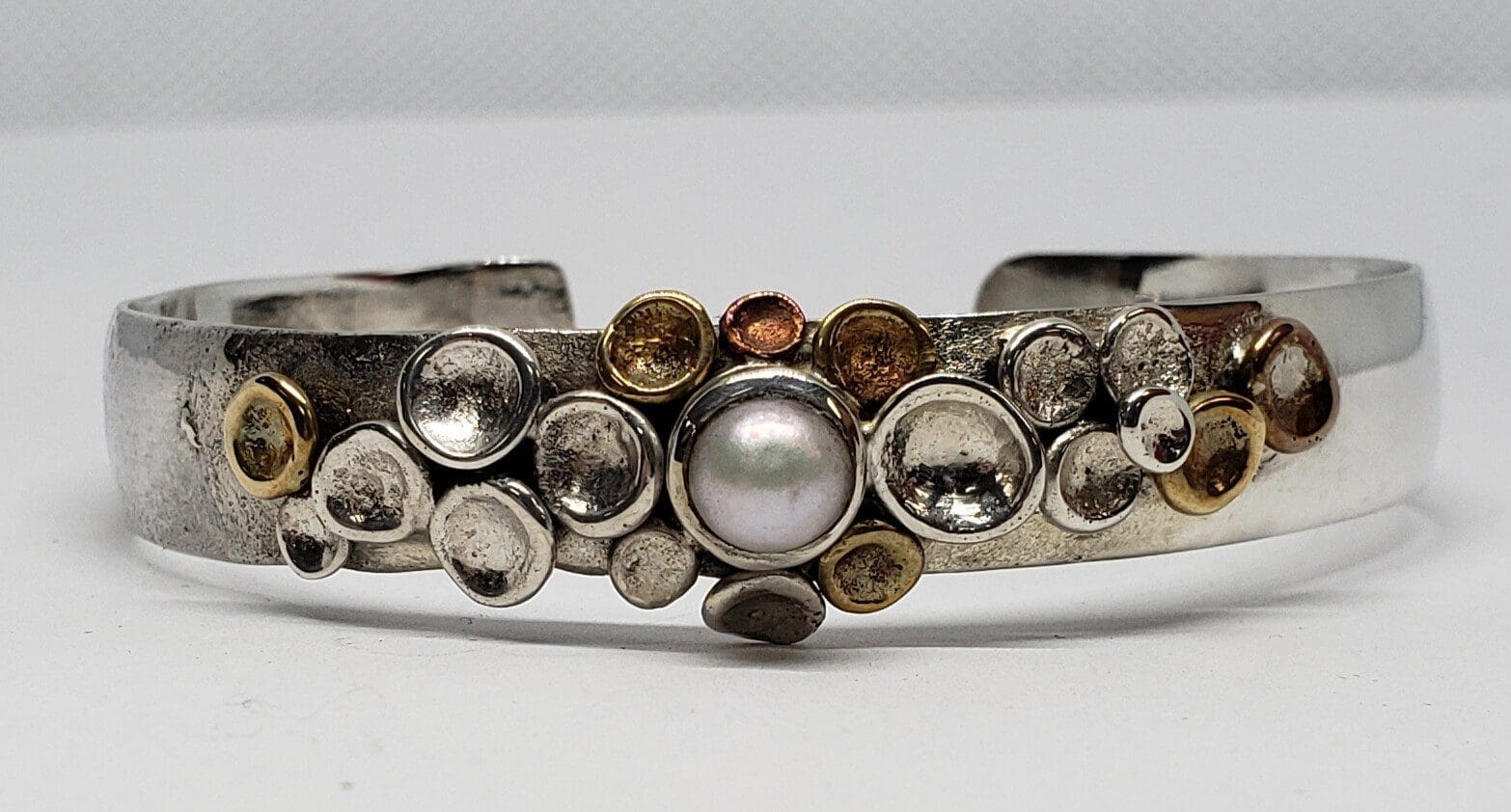 Silver bracelet with pearl and decorative circles.