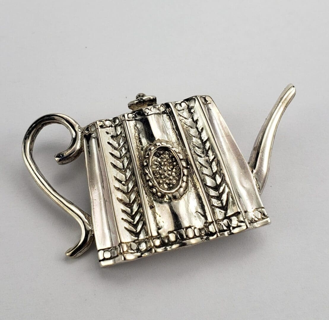 Ornate silver teapot with intricate design.