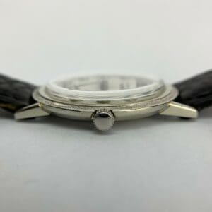 Silver wristwatch with black leather strap.