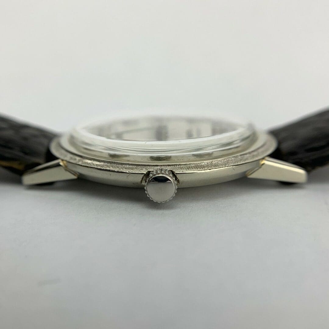 Silver wristwatch with black leather strap.