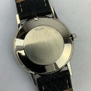 Watch back with black leather strap.