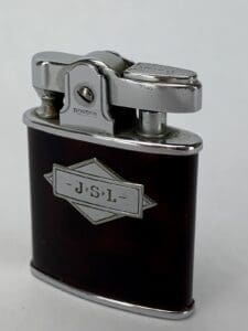 Vintage metal lighter with engraved initials.