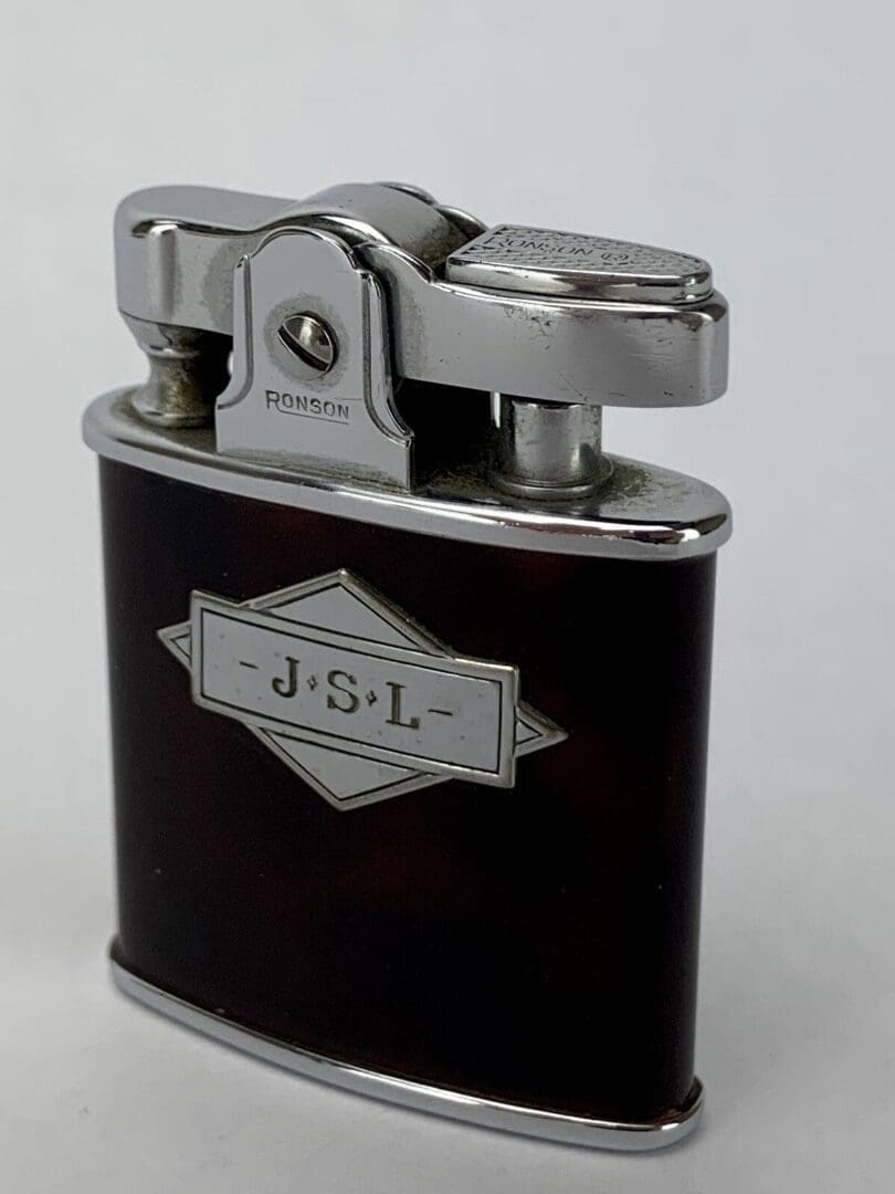 Vintage metal lighter with engraved initials.